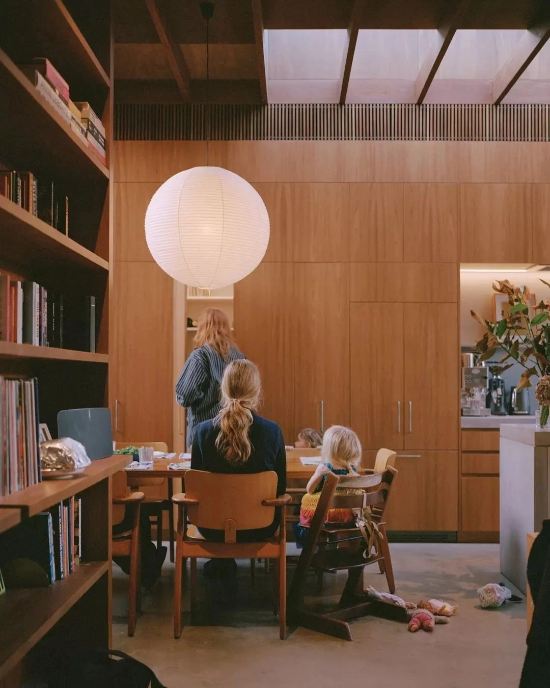 Warm wood home-office — paper lantern, books, family at the table.